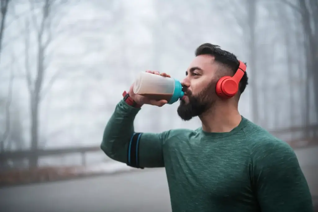 Man drinking a high protein shake outdoors after a run