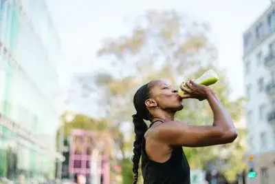 Woman drinking collagen protein shake outdoors after a workout